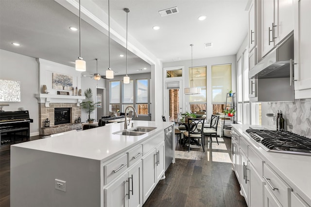 kitchen with visible vents, dark wood finished floors, stainless steel appliances, a fireplace, and a sink