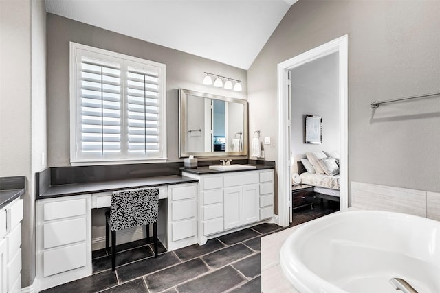 bathroom with lofted ceiling, tile patterned floors, a bath, and vanity