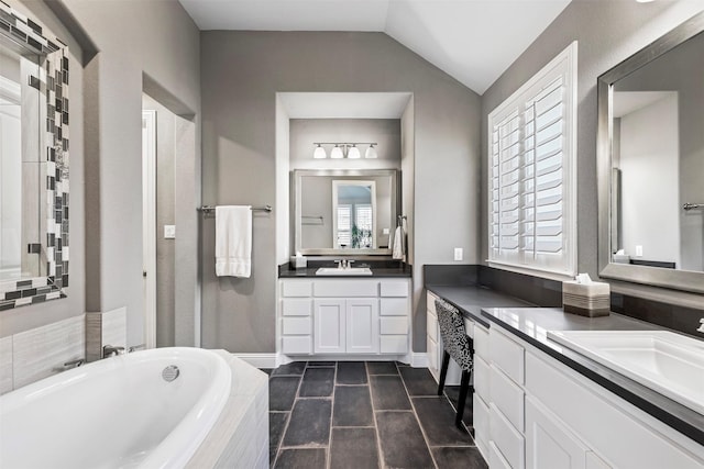 bathroom featuring lofted ceiling, two vanities, a sink, and a bath