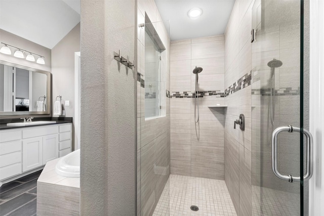 full bathroom featuring lofted ceiling, a stall shower, a garden tub, and vanity