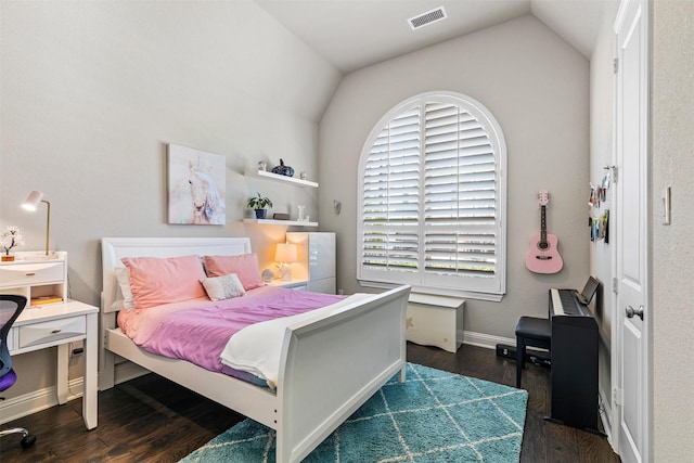 bedroom with visible vents, vaulted ceiling, baseboards, and wood finished floors