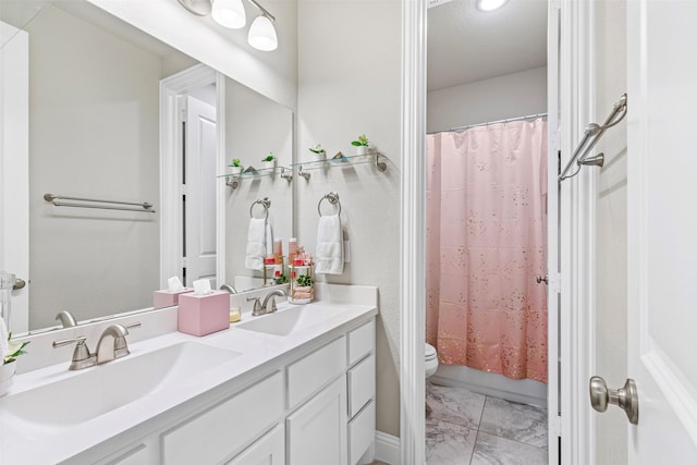 bathroom featuring marble finish floor, a sink, toilet, and double vanity