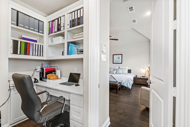 office area with dark wood-style flooring, visible vents, and built in desk