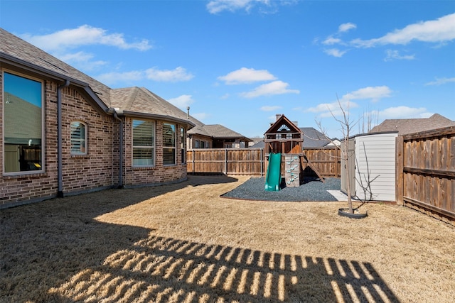 view of yard with an outbuilding, a storage shed, a playground, and a fenced backyard