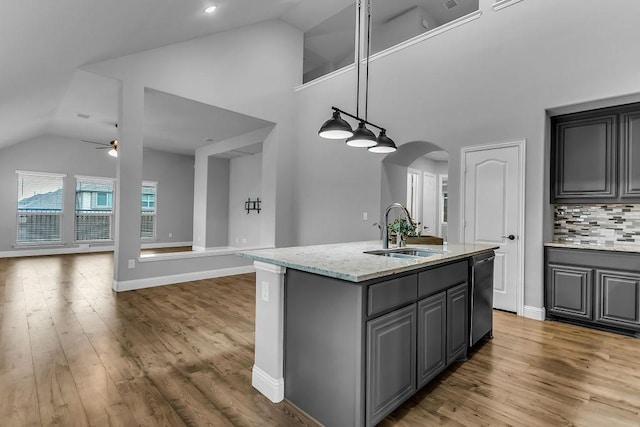 kitchen with dishwashing machine, gray cabinets, arched walkways, and a sink