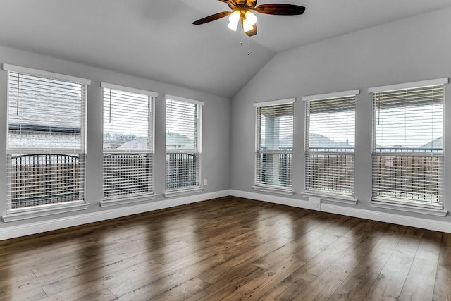 empty room featuring a ceiling fan, vaulted ceiling, dark wood-style floors, and baseboards