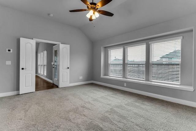 carpeted empty room featuring baseboards, a ceiling fan, and vaulted ceiling