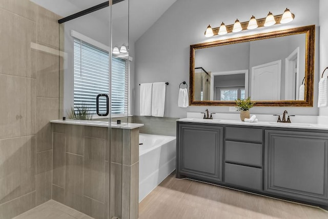 full bath with a sink, a bath, a tile shower, and vaulted ceiling