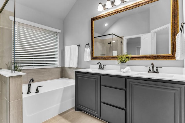 full bath with a sink, lofted ceiling, a garden tub, and a shower stall