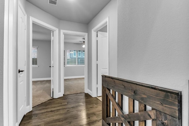 hallway featuring dark wood-style floors, visible vents, and baseboards