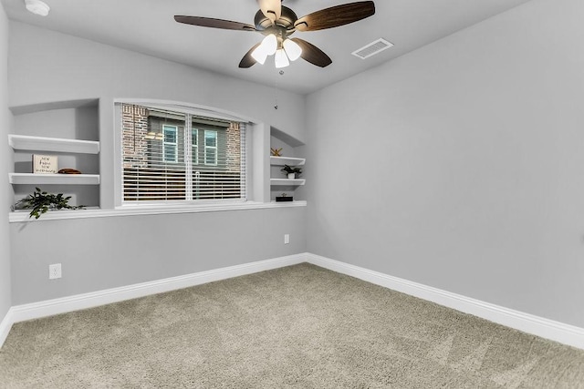 empty room with built in features, a ceiling fan, baseboards, visible vents, and carpet flooring