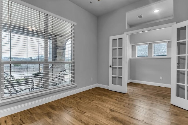 empty room featuring french doors, baseboards, visible vents, and wood finished floors