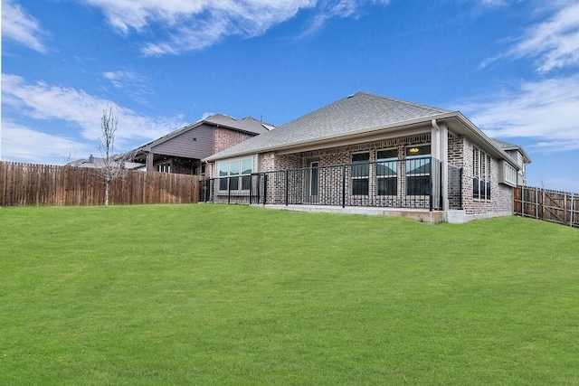 back of property with a yard, brick siding, and a fenced backyard