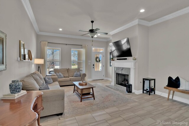 living room featuring ceiling fan, recessed lighting, a premium fireplace, baseboards, and crown molding