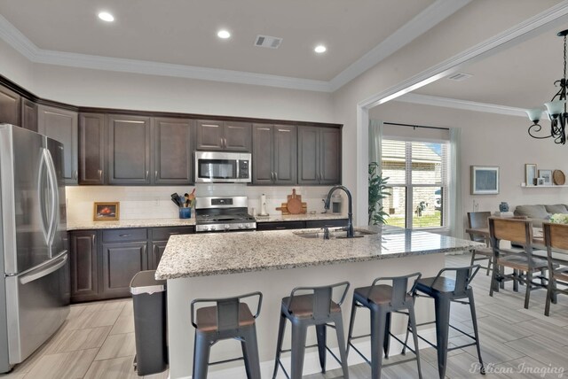 kitchen featuring stainless steel appliances, a sink, backsplash, and dark brown cabinetry