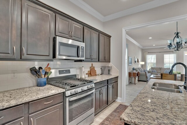 kitchen featuring stainless steel appliances, tasteful backsplash, ornamental molding, a sink, and dark brown cabinetry