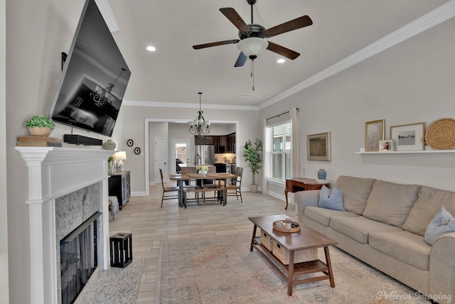 living area with ornamental molding, a fireplace, baseboards, and ceiling fan with notable chandelier