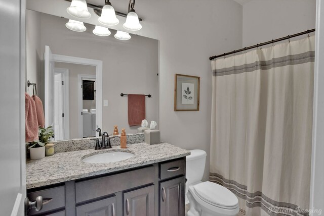 bathroom with washer and clothes dryer, toilet, and vanity