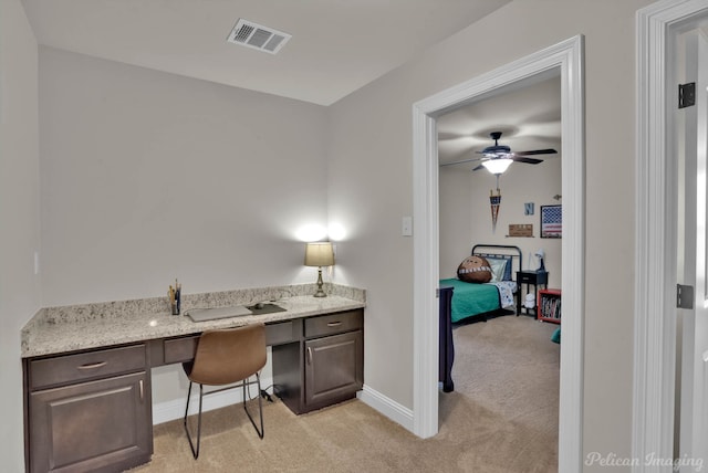 office space featuring baseboards, built in study area, visible vents, and light colored carpet