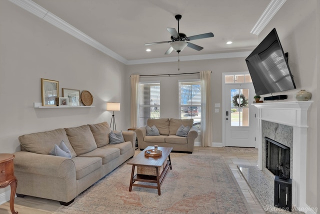 living area featuring recessed lighting, ornamental molding, a high end fireplace, a ceiling fan, and baseboards