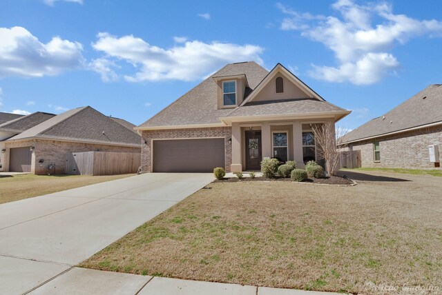 view of front of home featuring driveway, brick siding, roof with shingles, an attached garage, and a front yard