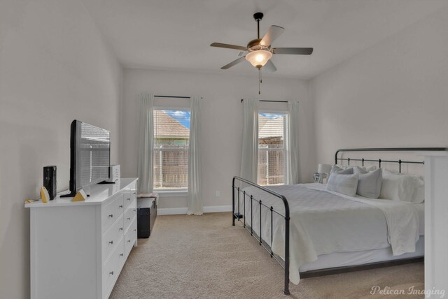 bedroom with ceiling fan, baseboards, and light colored carpet