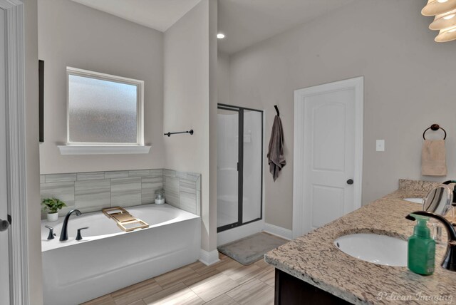 bathroom with double vanity, a stall shower, a sink, baseboards, and a bath