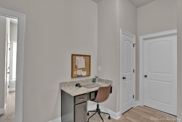 office featuring built in study area, light wood finished floors, and baseboards