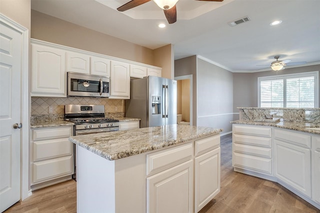 kitchen with stainless steel appliances, visible vents, light wood-style floors, and backsplash