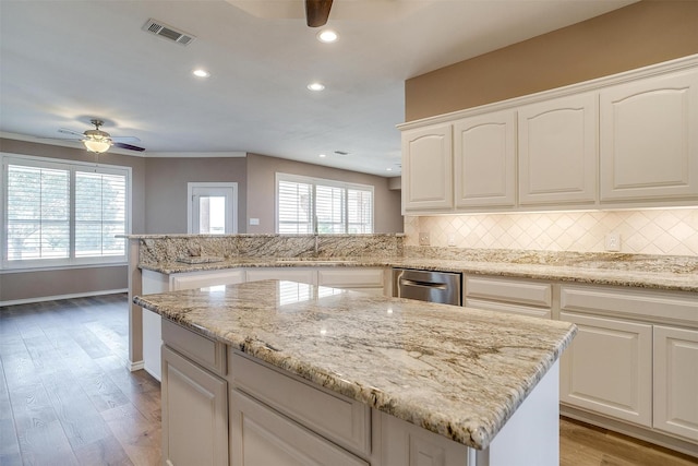 kitchen featuring ceiling fan, a peninsula, backsplash, and visible vents