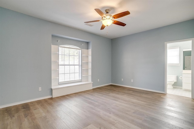 spare room featuring baseboards, ceiling fan, visible vents, and wood finished floors