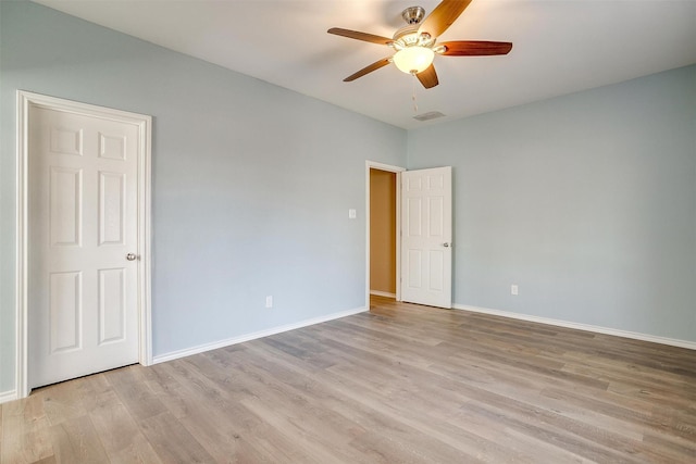 empty room featuring ceiling fan, light wood-type flooring, visible vents, and baseboards