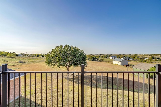 view of yard with fence, an outbuilding, and a rural view