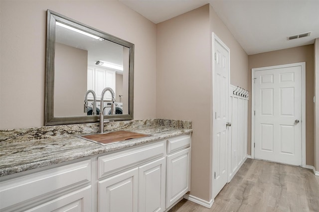 bathroom featuring vanity, wood finished floors, visible vents, and baseboards