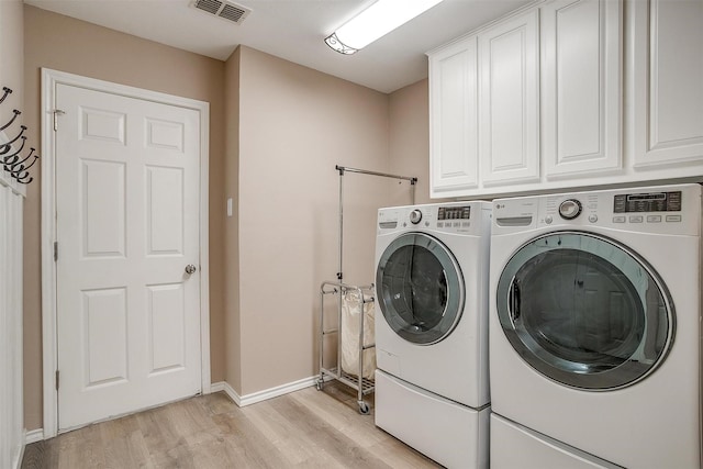 laundry area with visible vents, washer and clothes dryer, light wood-type flooring, and cabinet space