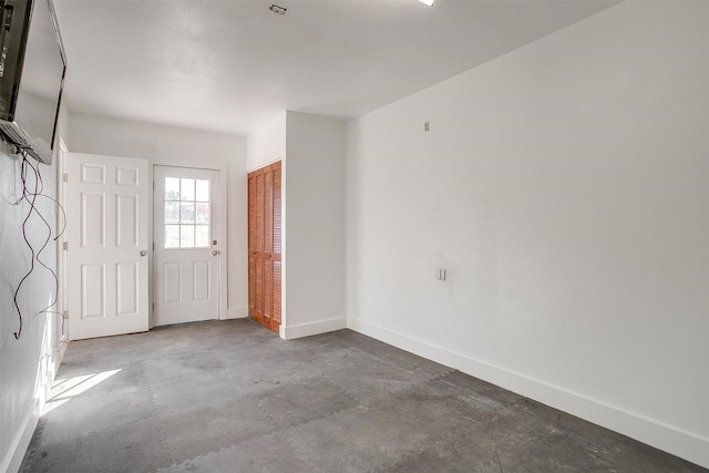 spare room featuring baseboards and concrete flooring