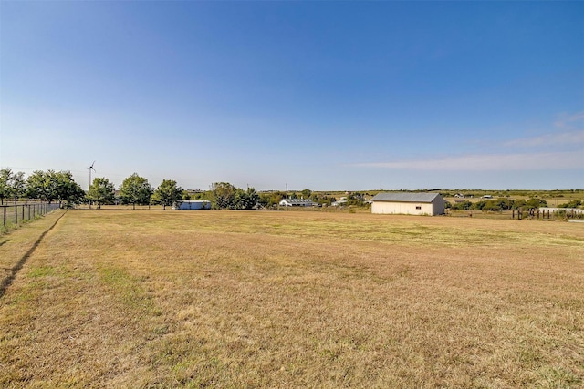 view of yard with fence, an outbuilding, and a rural view