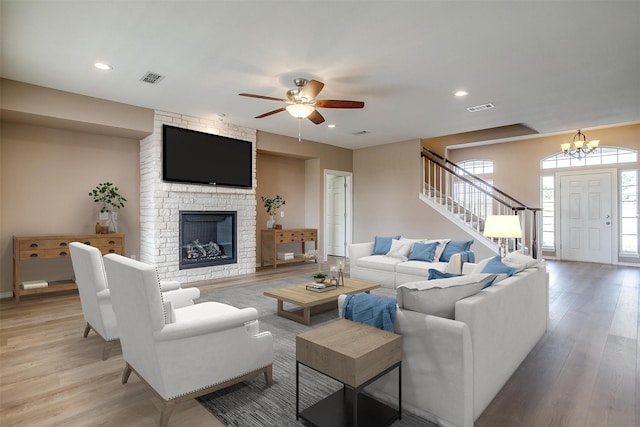 living area with light wood-style flooring, recessed lighting, a fireplace, visible vents, and stairs