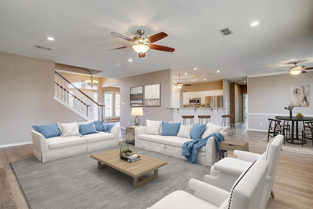 living area with light wood-type flooring, visible vents, stairway, and recessed lighting