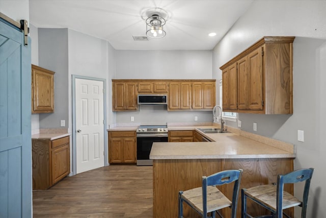 kitchen with stainless steel appliances, visible vents, a barn door, a sink, and a peninsula