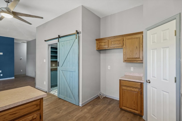 kitchen featuring light countertops, a barn door, brown cabinetry, and dark wood finished floors