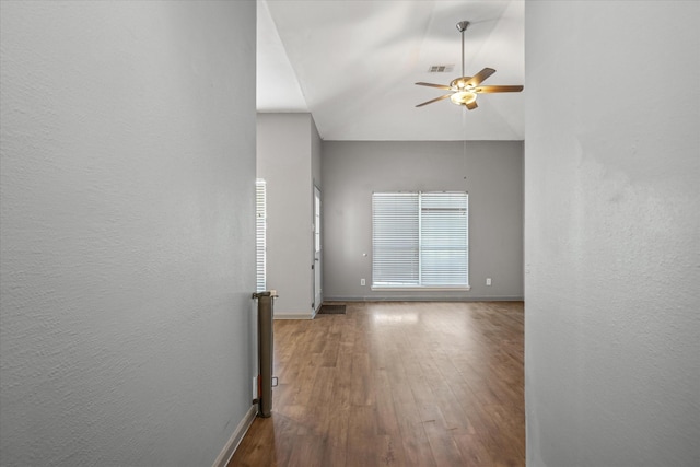 spare room with baseboards, a ceiling fan, wood finished floors, and a textured wall