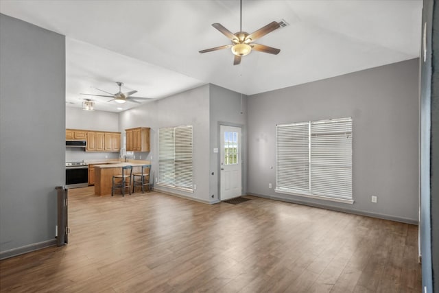 unfurnished living room with wood finished floors, a ceiling fan, and baseboards