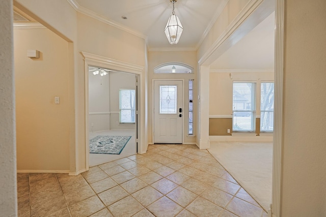 entryway with light carpet, ornamental molding, plenty of natural light, and light tile patterned flooring