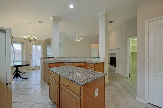 kitchen featuring lofted ceiling, visible vents, ornamental molding, freestanding refrigerator, and brown cabinets