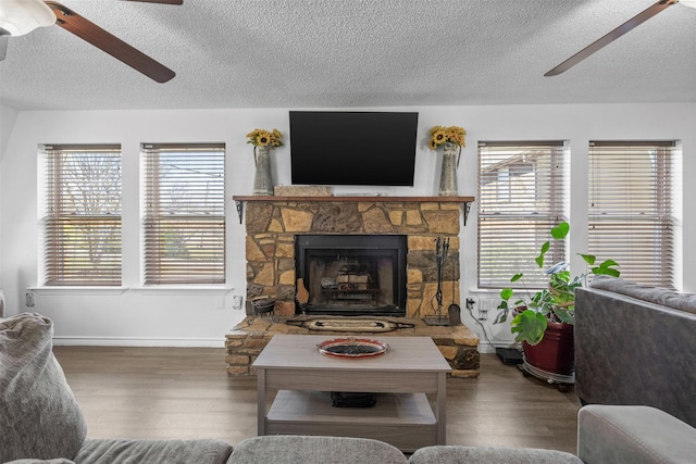 living area with a fireplace, ceiling fan, a textured ceiling, and wood finished floors