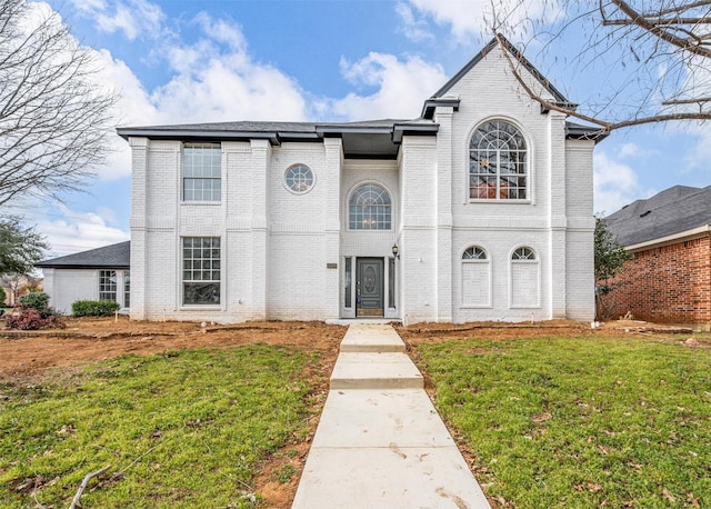 french provincial home featuring a front yard and brick siding