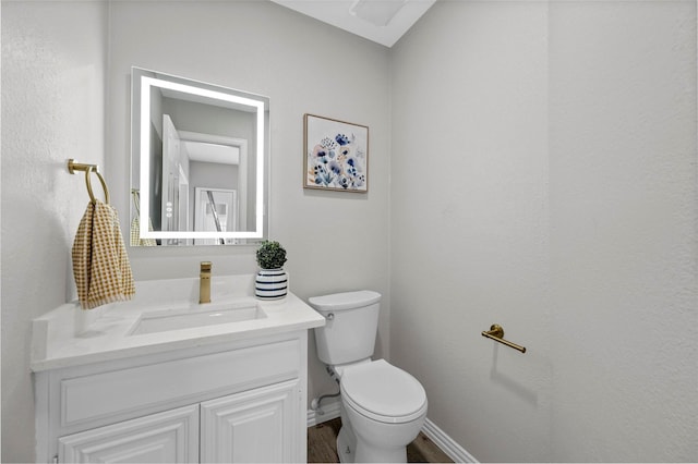 bathroom featuring wood finished floors, vanity, toilet, and baseboards