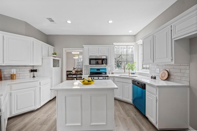 kitchen with light countertops, appliances with stainless steel finishes, a sink, and white cabinetry