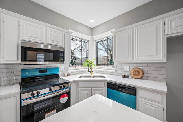 kitchen with appliances with stainless steel finishes, a sink, white cabinetry, and tasteful backsplash